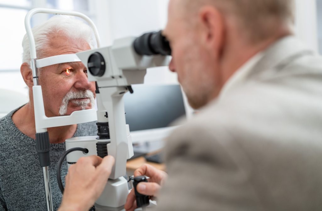 An older adult during a slit-lamp eye exam while an optometrist looks for the cause of their vision problems at night.