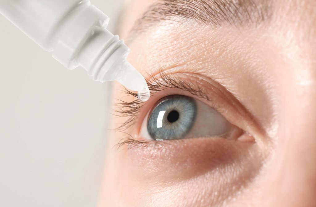 Close up of a person putting eye drops into their eye.