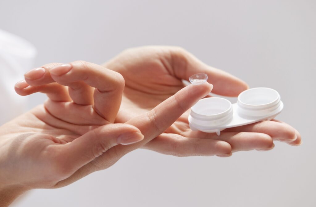 A close-up photo of a pair of hands holding a contact lens and it's protective case.