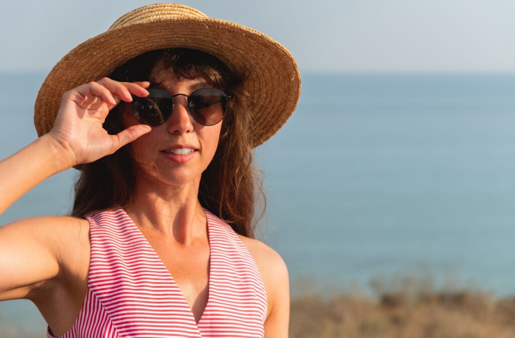A person adjusting their sunglasses outdoors.