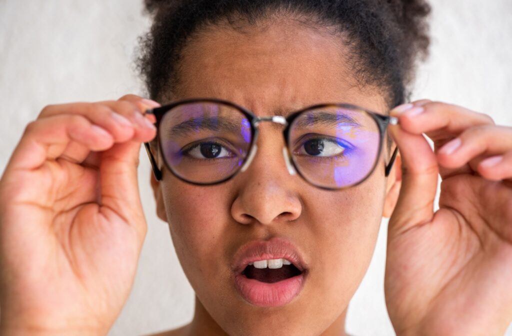 A person holds their glasses away, looking confused and cross-eyed.