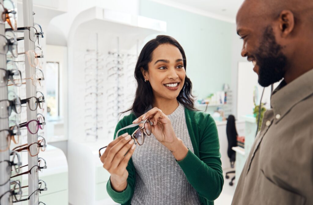 A person smiles while being shown glasses in an optical store.
