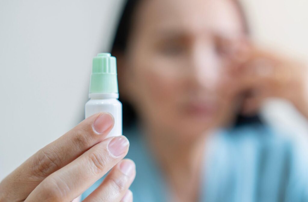 A person holding out a bottle of eye drops.
